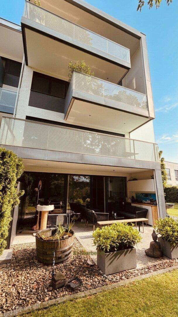 Moderne Gebäudefassade mit mehreren Balkonen und einer großzügigen Terrasse im Erdgeschoss.