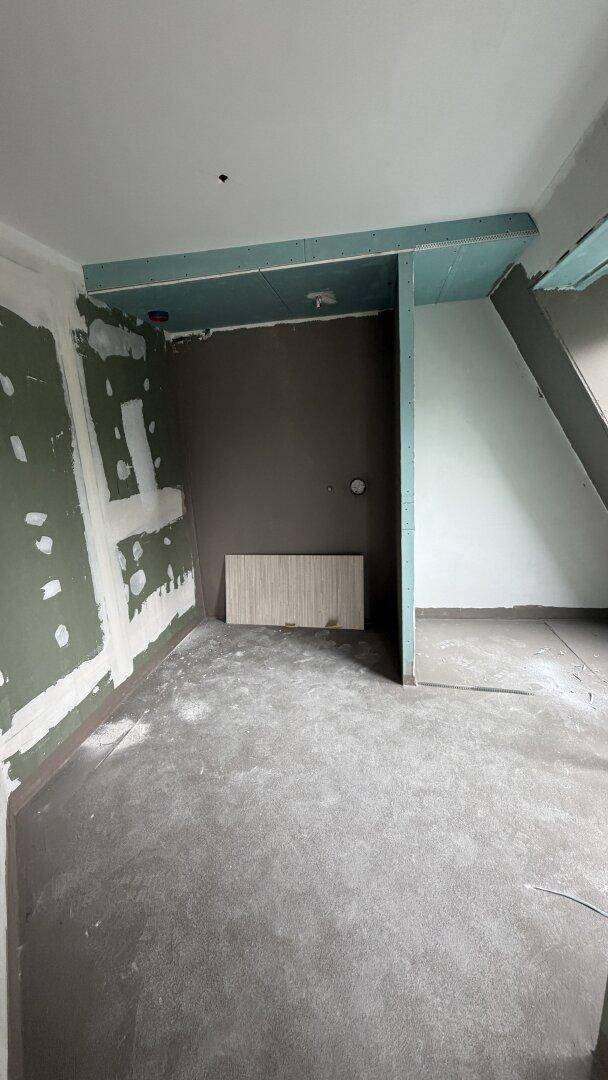 Raum im Rohbauzustand mit Trockenbauwänden und vorbereiteten Installationen.