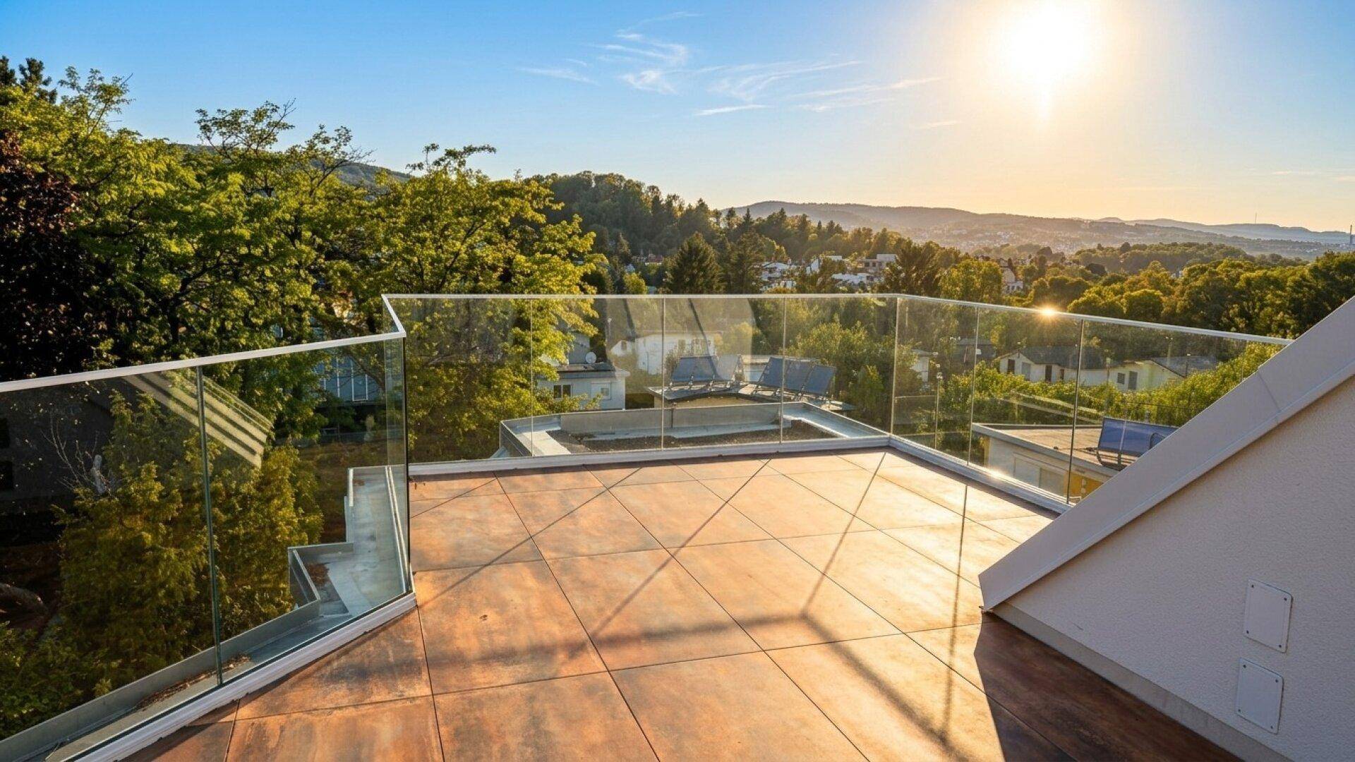 Sonniger Dachterrassenbereich mit Glasgeländer und atemberaubendem Panoramablick über die Landschaft bei Sonnenuntergang.