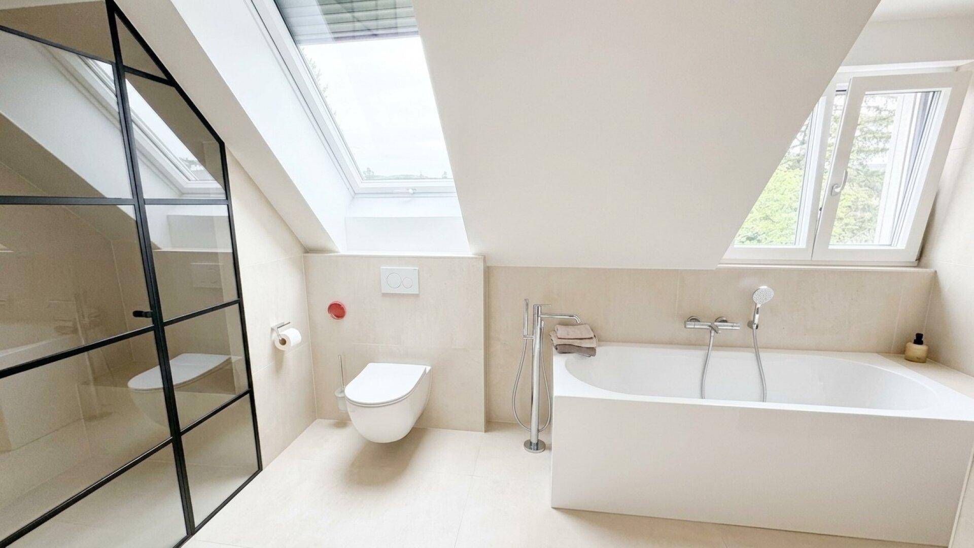 Modernes Badezimmer mit Badewanne, bodengleicher Dusche und Oberlicht unter Dachschräge.
