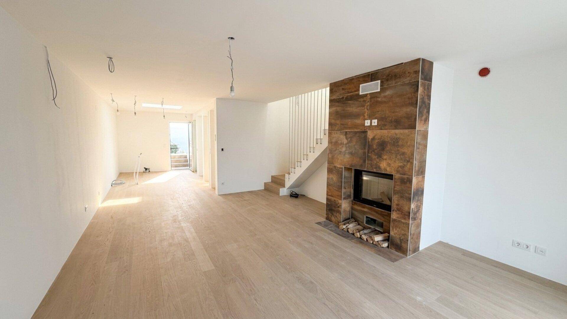 Geräumiger Wohnbereich mit modernem Kamin, Holzfußboden und eleganter Treppe.