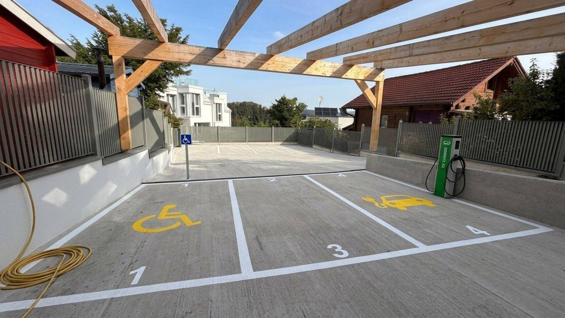 Außenparkplätze mit Markierungen für Elektrofahrzeuge und barrierefreie Stellplätze.