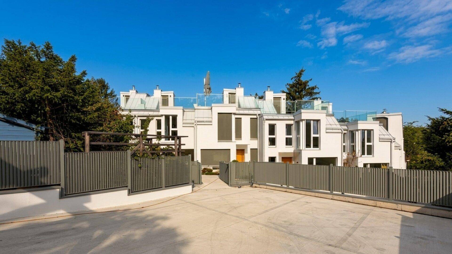 Moderne Wohnanlage mit weißer Fassade und klaren Linien unter blauem Himmel.
