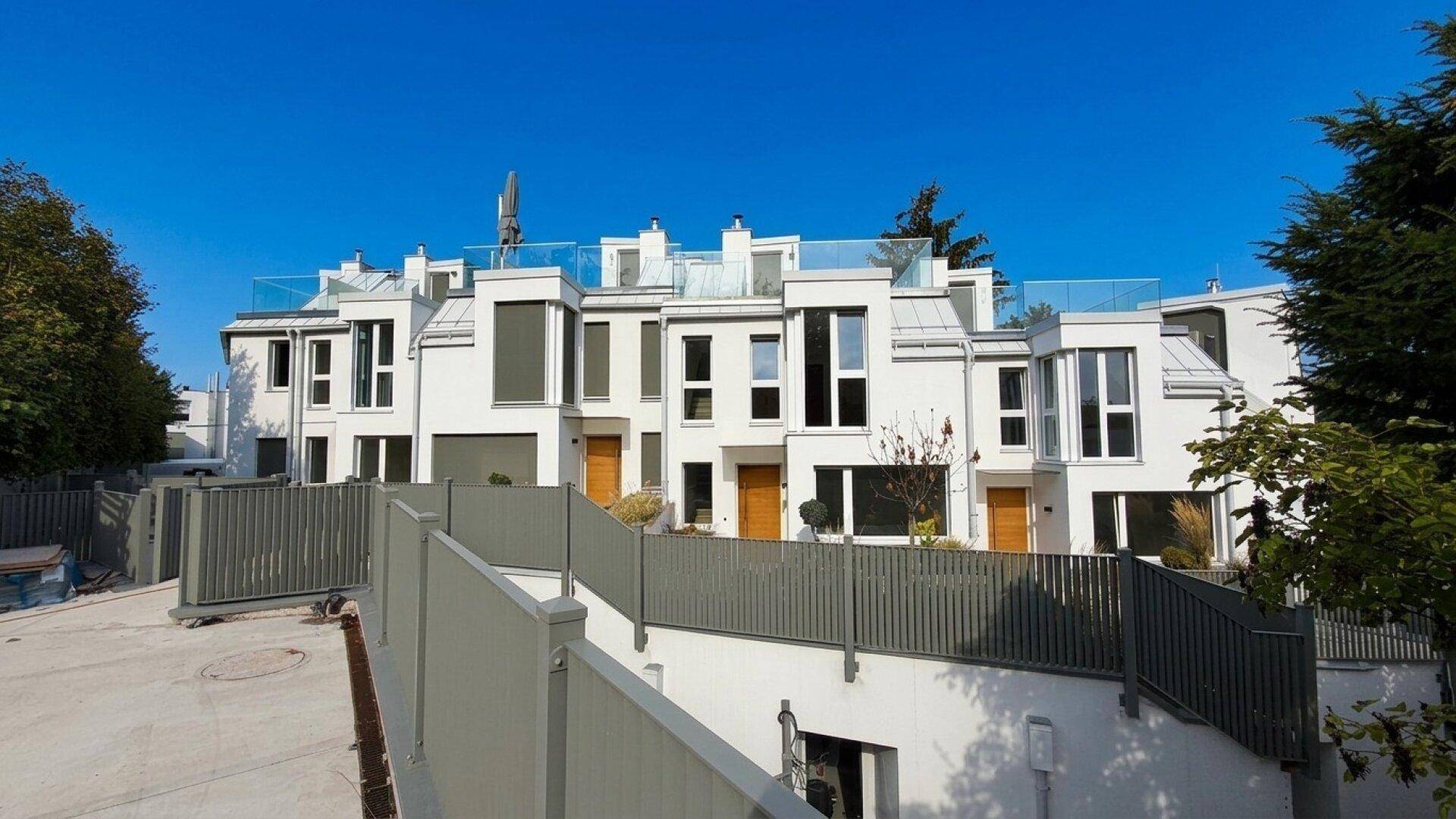 Moderne Reihenhäuser mit weißer Fassade und Zugang zu den unteren Ebenen.