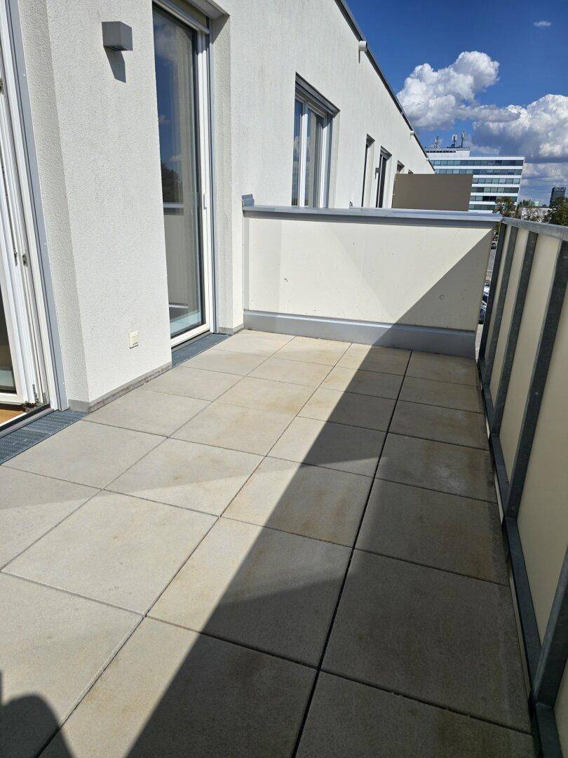 Heller Balkon mit Fliesenboden und Blick auf die Umgebung, ideal für Entspannung im Freien.