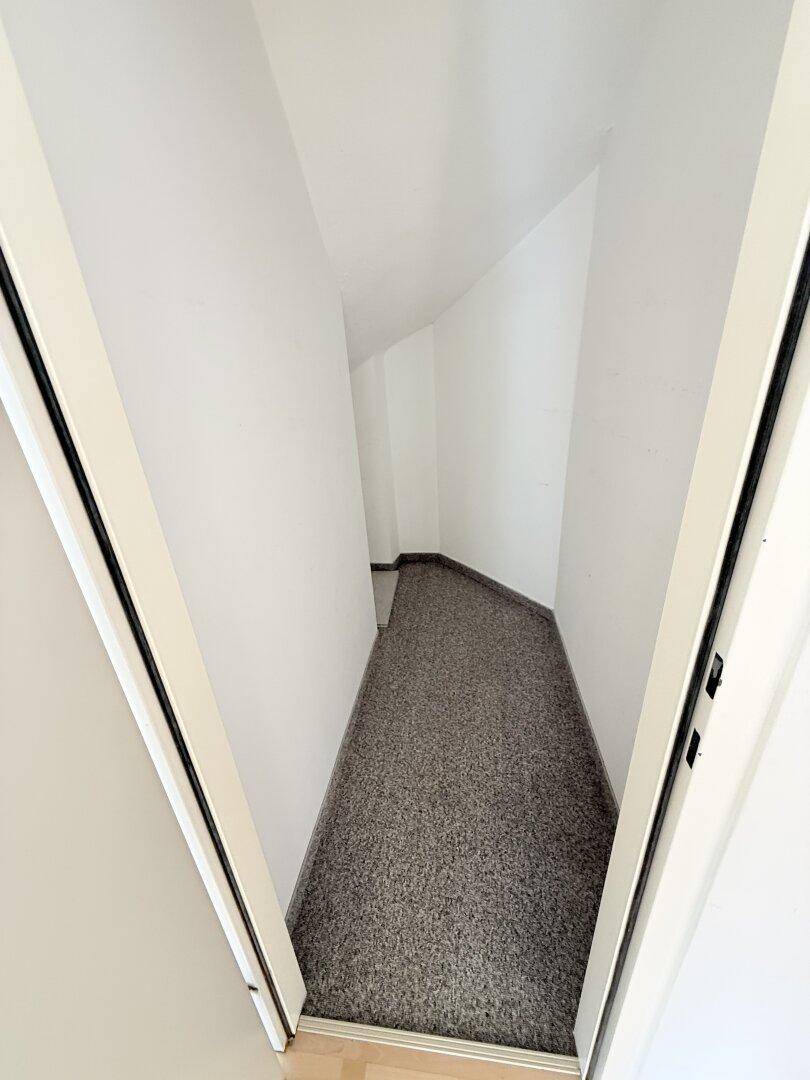 Kleiner Abstellraum mit Teppichboden und schrägen Wänden im Dachgeschoss.