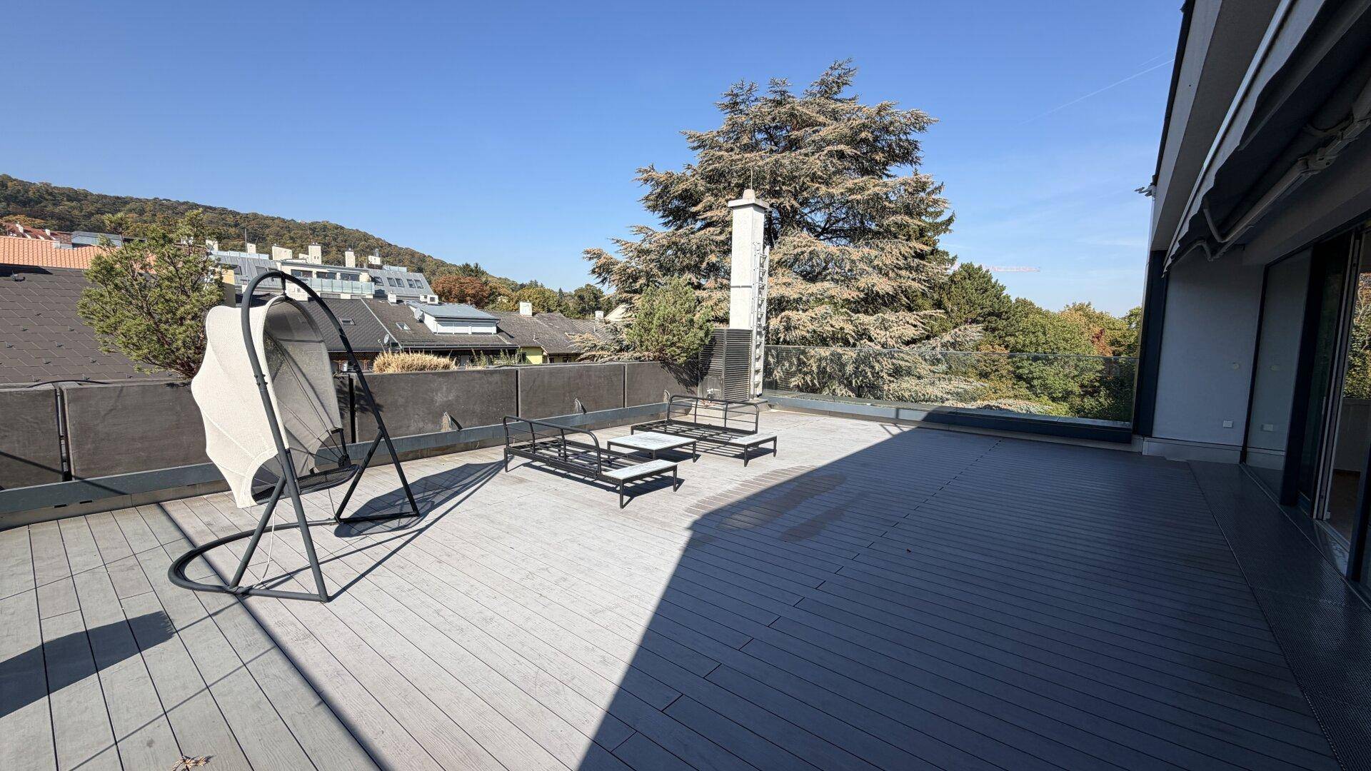 Große Sonnenterrasse mit Holzdeck, Gartenmöbeln und weitem Blick ins Grüne.