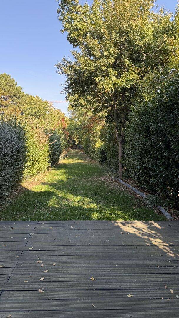 Langer, gepflegter Gartenbereich mit Rasenfläche und hohen Hecken, ideal für Entspannung im Grünen.