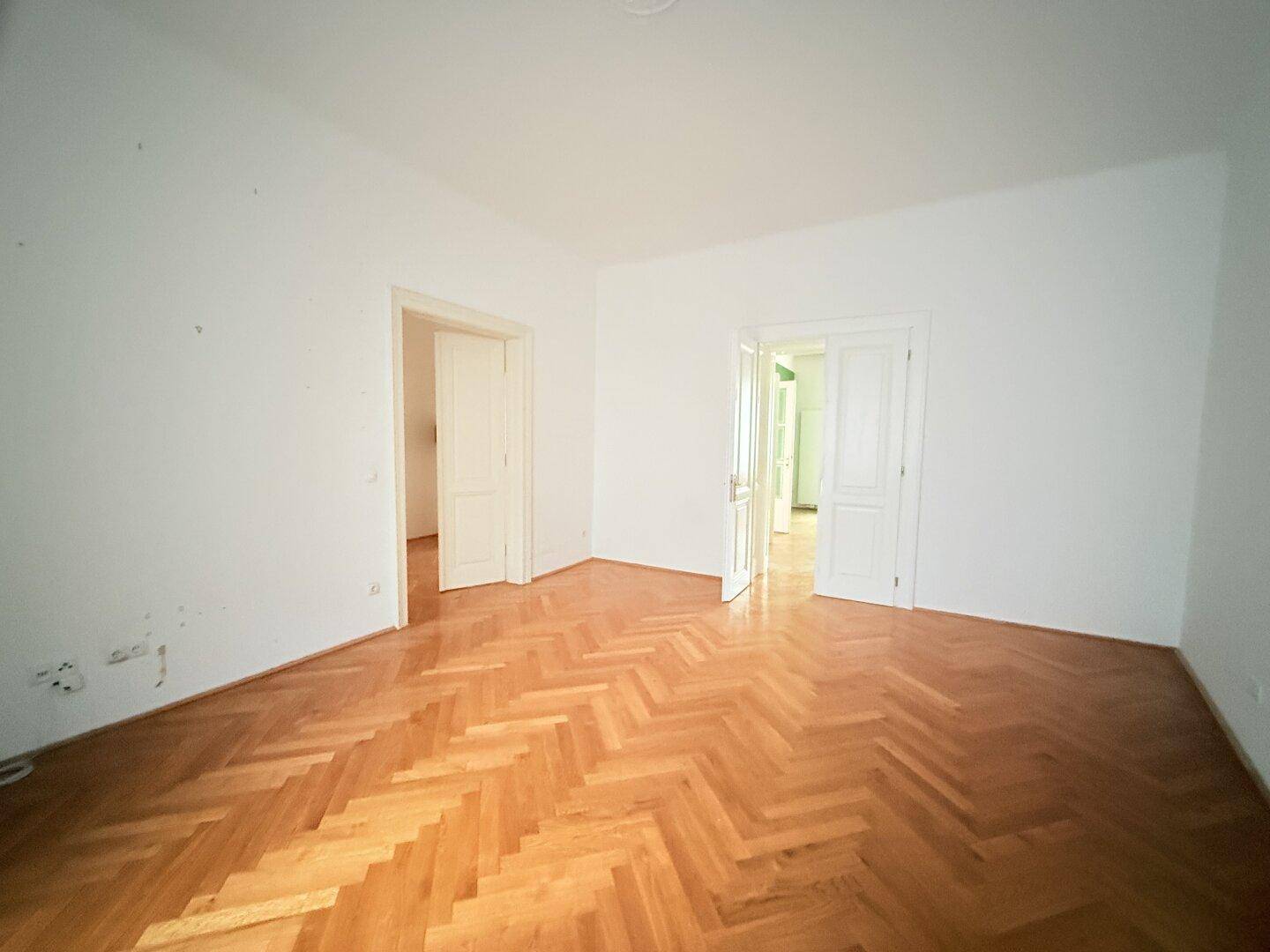 Geräumiges Zimmer mit Fischgrätparkett und hohen Türen, bereit zur individuellen Gestaltung.