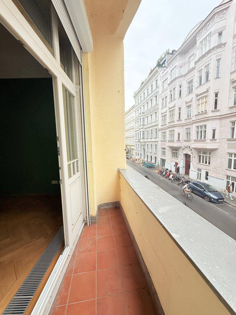 Schmaler Balkon mit Terrakottafliesen und Blick auf die belebte Stadtstraße.