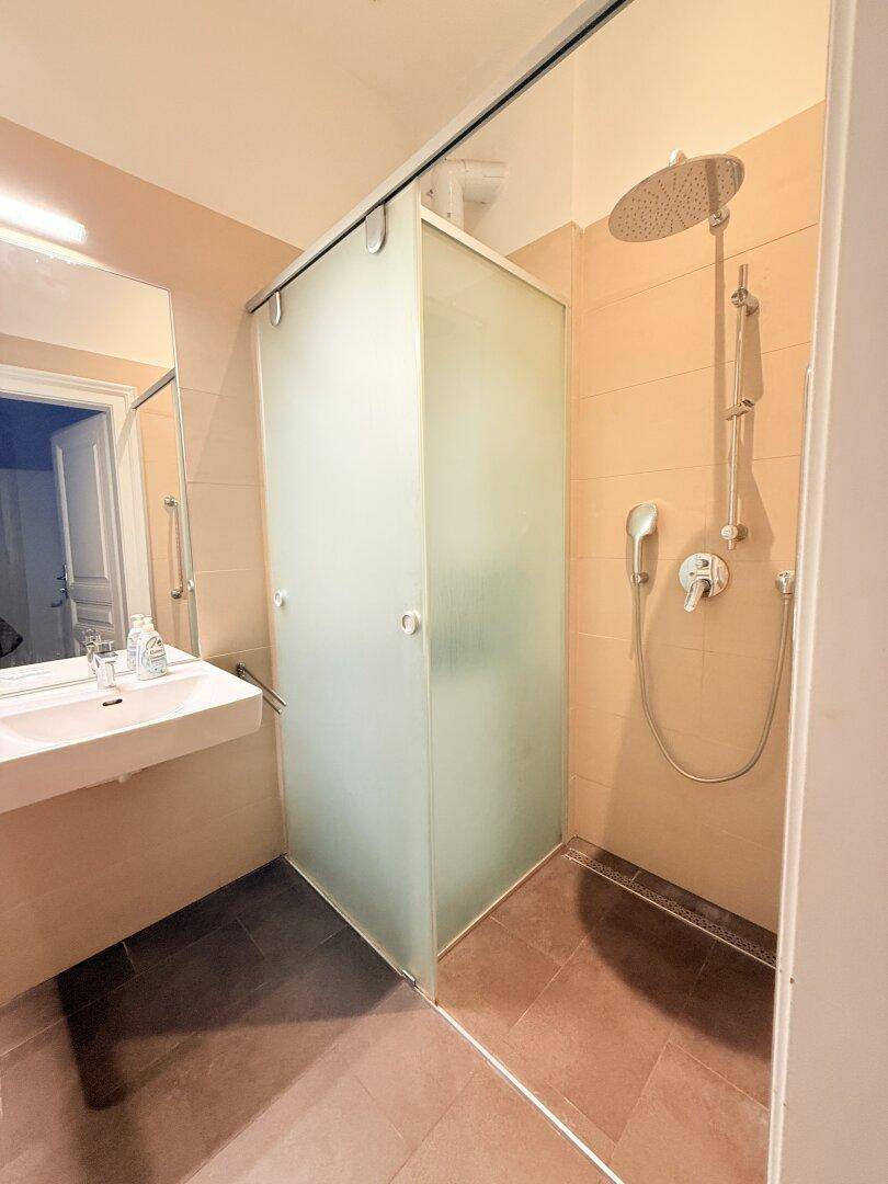 Modernes Badezimmer mit ebenerdiger Dusche, Regenbrause und Waschbecken.