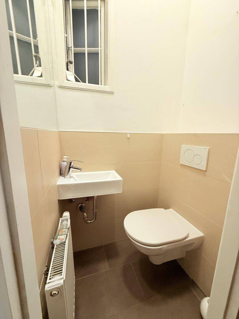 Kleines Gäste-WC mit Wand-WC, Waschbecken und Fenster für natürliche Belüftung.