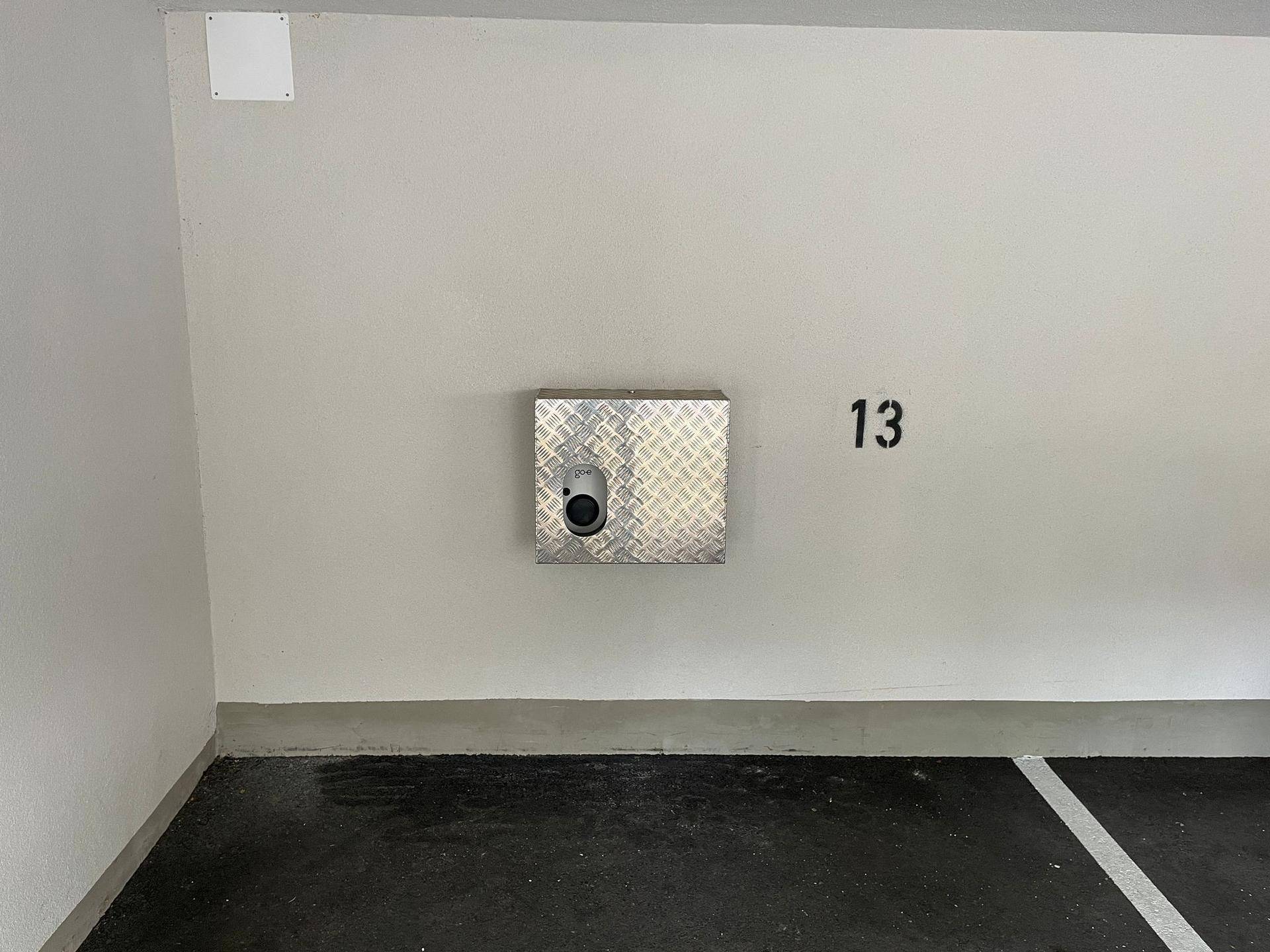 Nahaufnahme der Elektrofahrzeug-Ladestation an der Wand des Tiefgaragenstellplatzes Nummer 13.