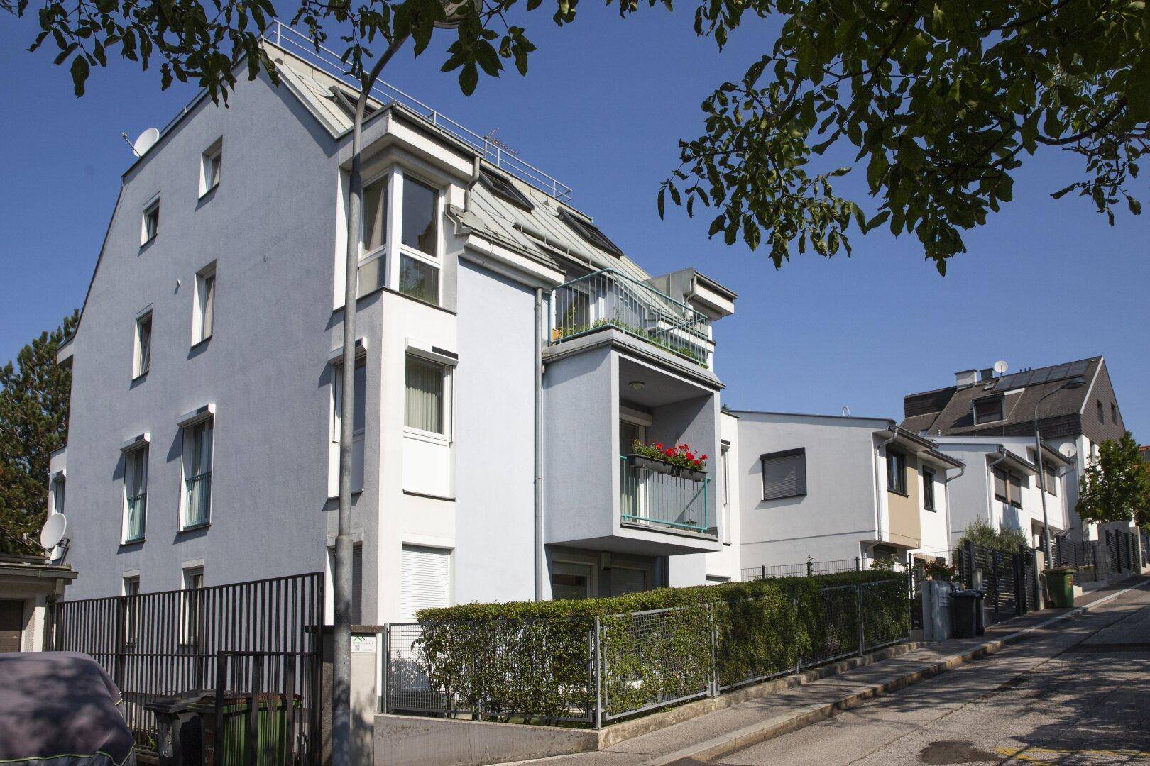 Modernes Mehrfamilienhaus mit Balkonen und großen Fenstern an einer ruhigen Straße gelegen.