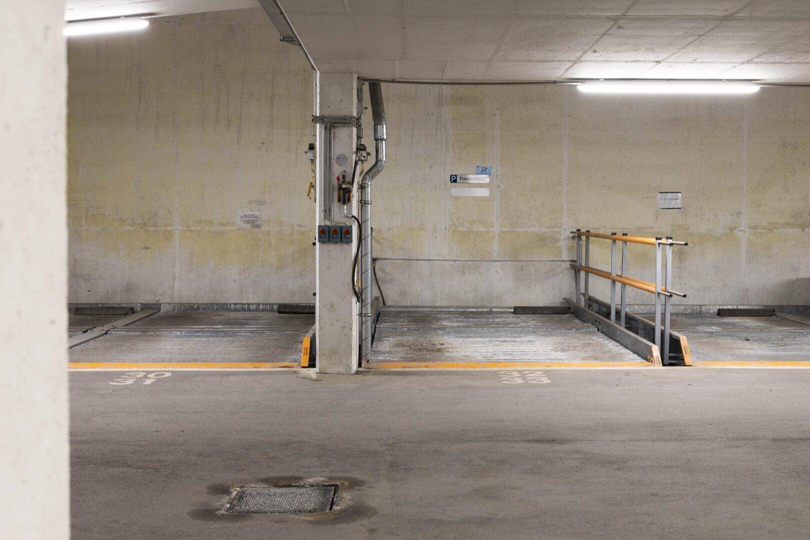 Tiefgarage mit Betonwänden und markierten Parkplätzen, gut beleuchtet.
