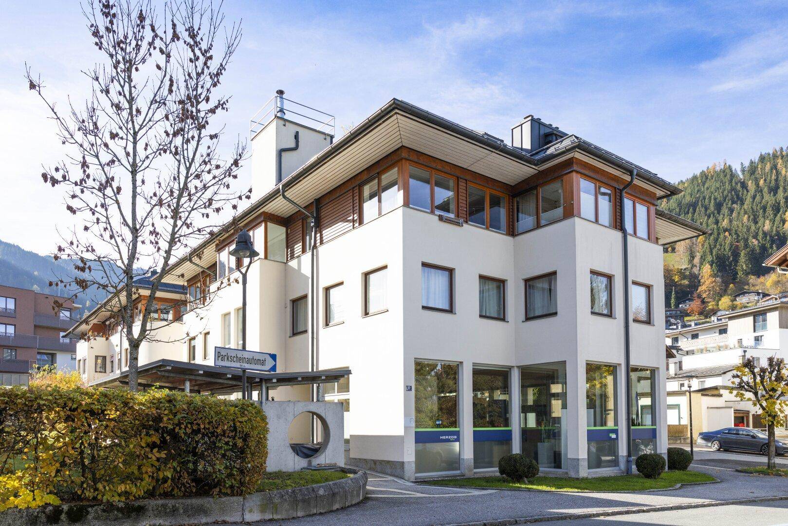 Modernes Gebäude mit großen Fenstern und Holzelementen in alpiner Umgebung.