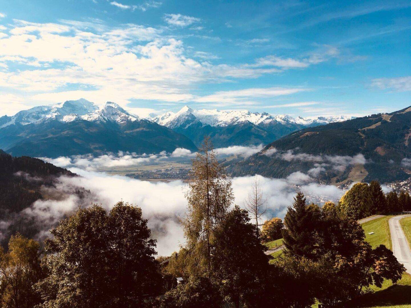 Atemberaubender Panoramablick auf schneebedeckte Berge und ein Tal mit Nebel.