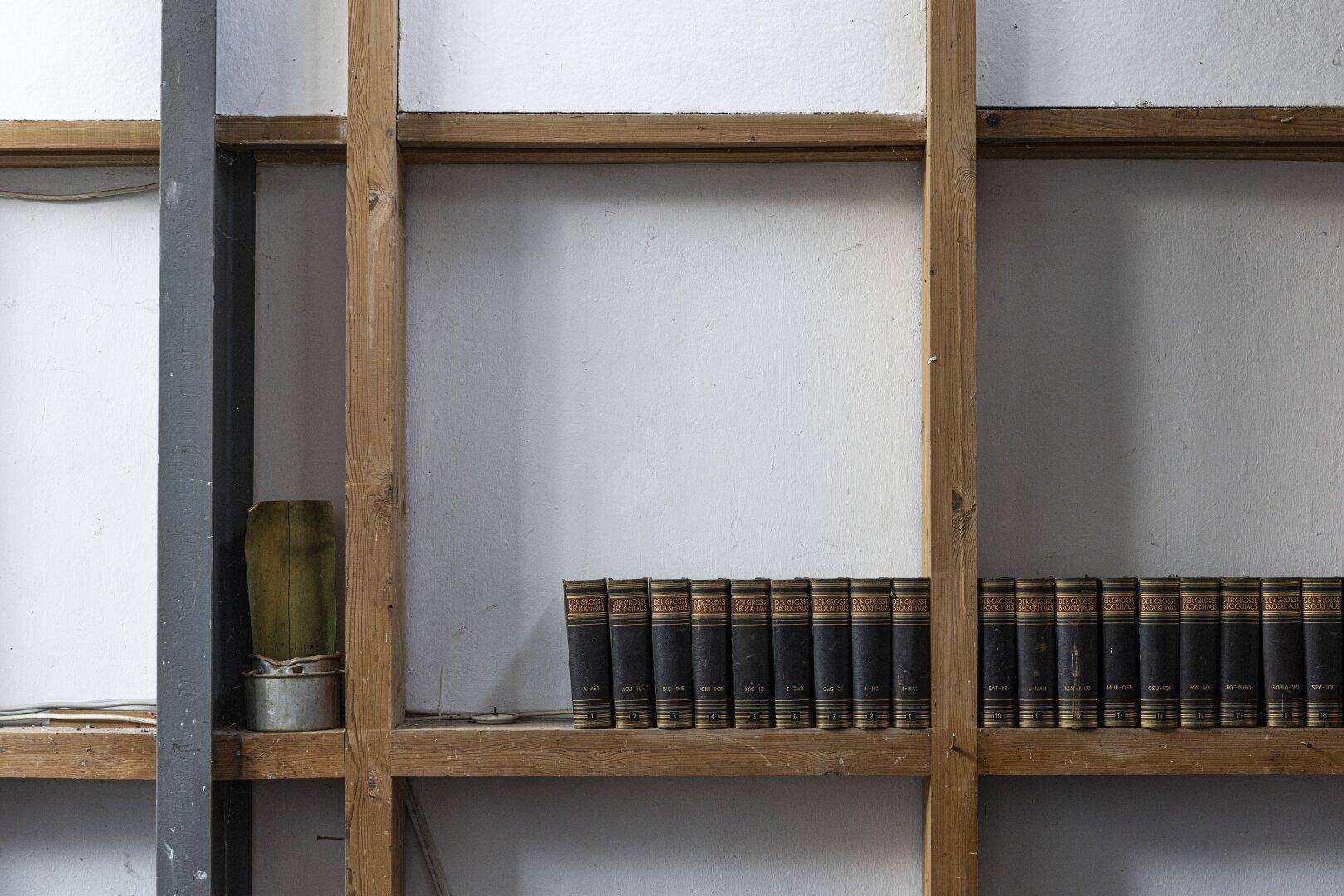 Regal mit alten Büchern und Holzrahmen, möglicherweise in einem Arbeits- oder Lagerbereich.