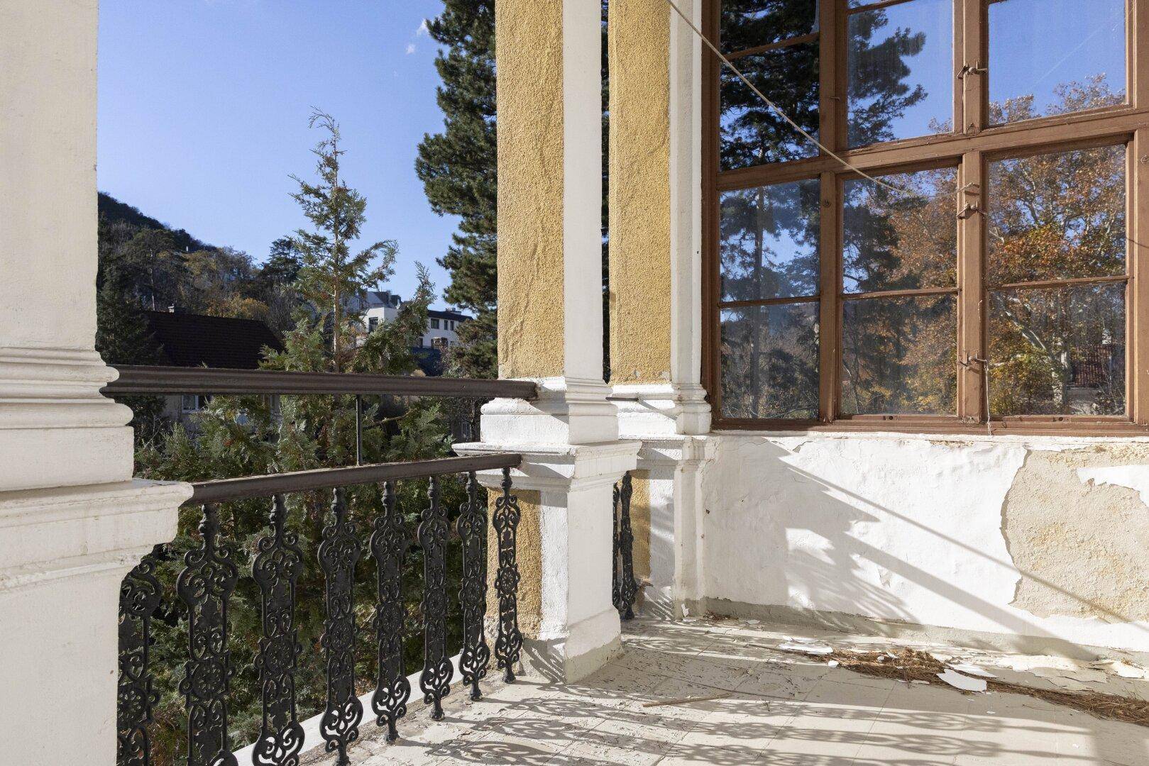 Balkon mit schmiedeeisernem Geländer und weitem Blick auf die umliegende grüne Landschaft.