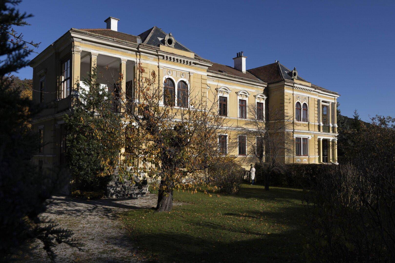 Prächtige historische Villa mit klassischer Architektur und weitläufigem Garten unter blauem Himmel.
