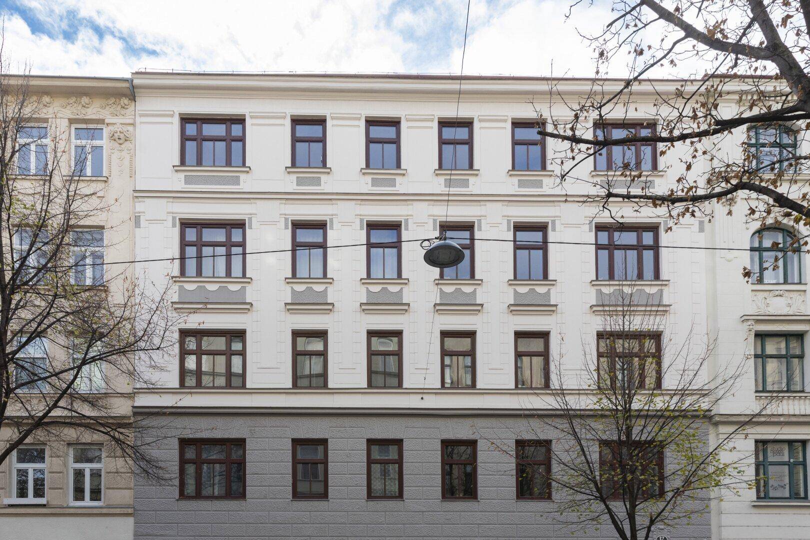 Klassische Fassade eines Mehrfamilienhauses mit zahlreichen Fenstern und traditionellen architektonischen Details.