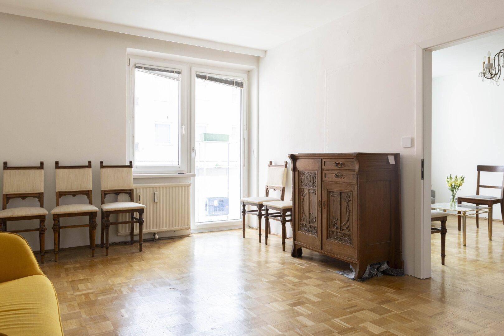Geräumiges Wohnzimmer mit Parkettboden, antiken Möbeln und großen Fenstern.