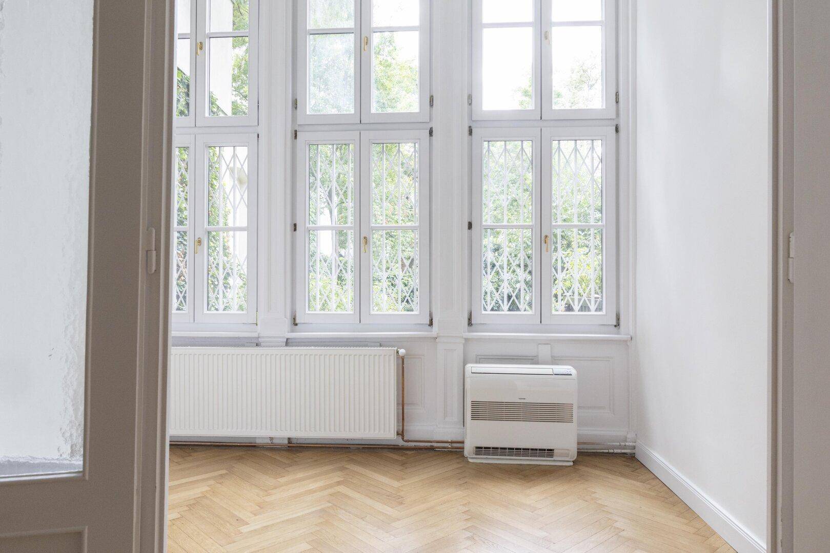 Heller Erkerbereich mit großen Fenstern und Blick ins Grüne, ideal für einen gemütlichen Sitzplatz.