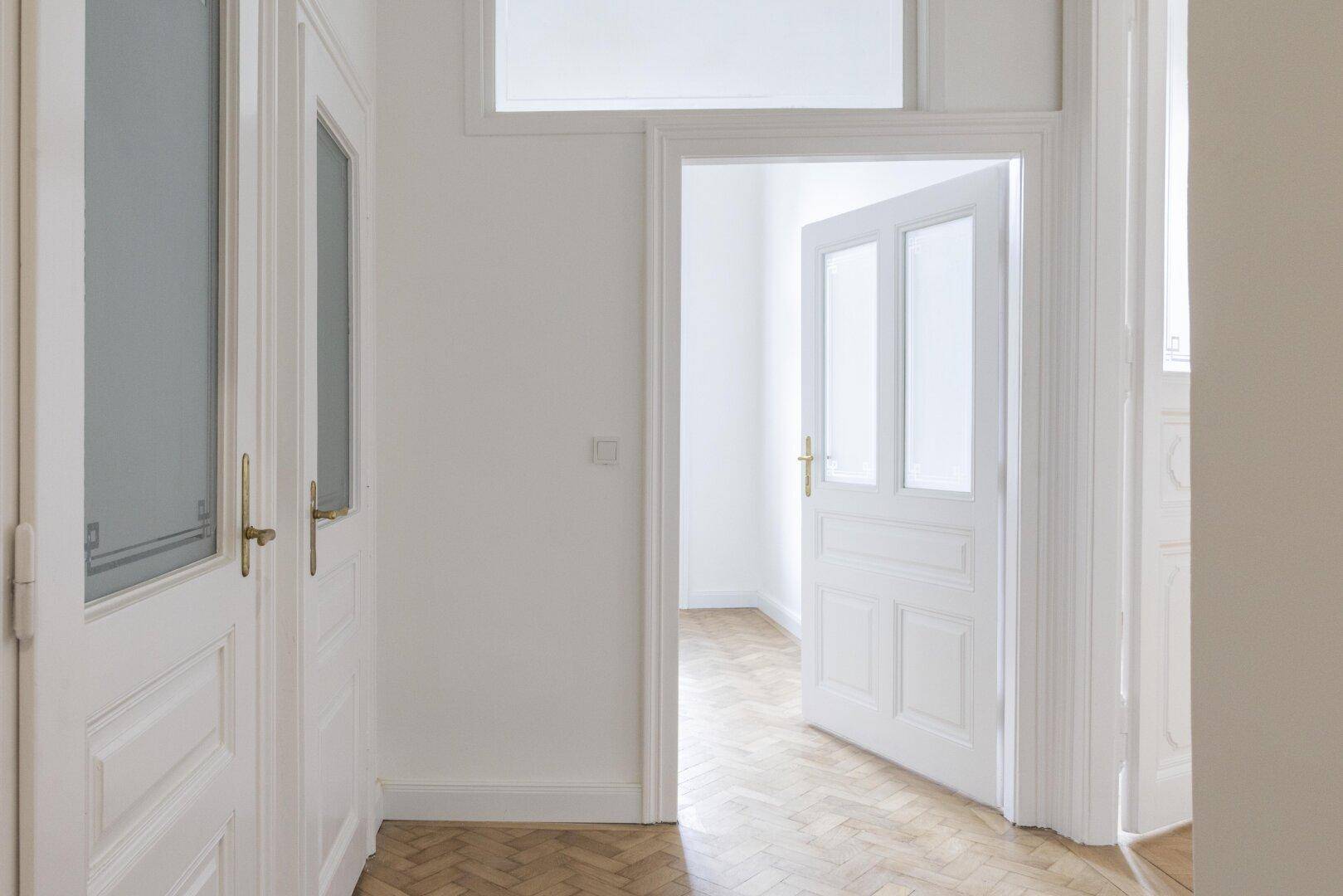 Heller Flur mit Parkettboden und mehreren Türen, die zu den verschiedenen Räumen der Wohnung führen.