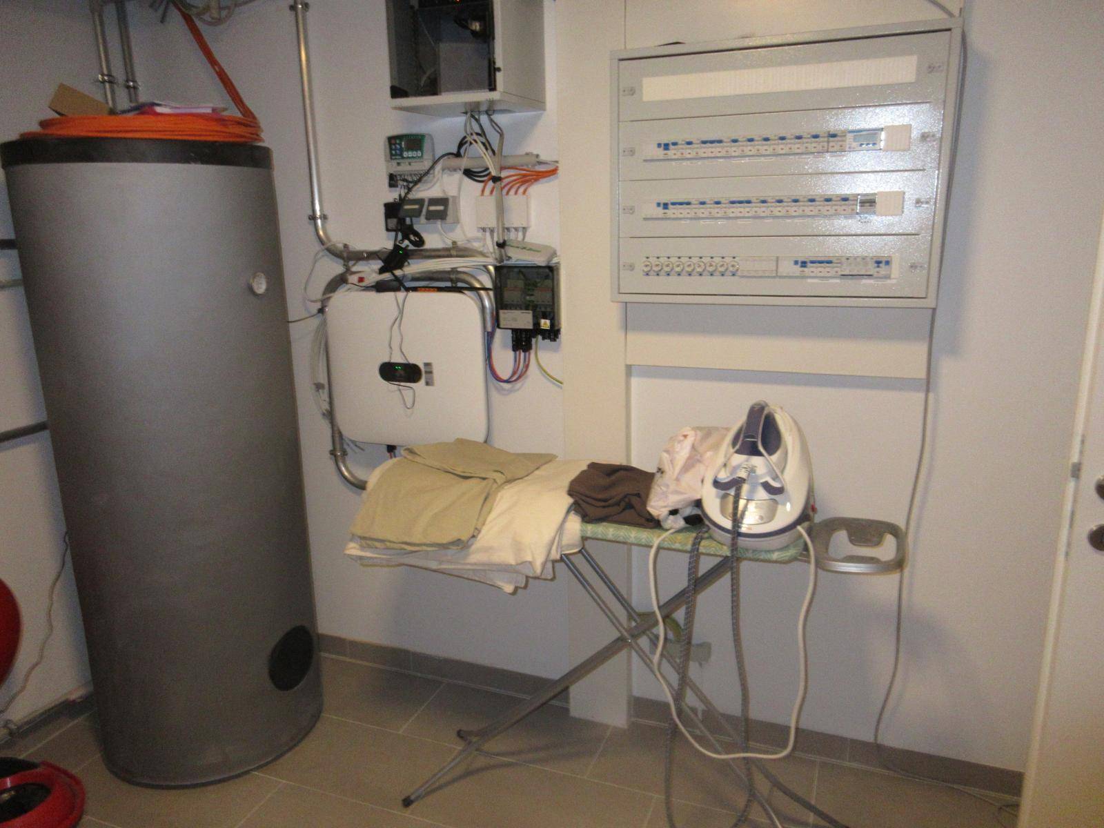 Praktischer Hauswirtschaftsraum mit Warmwasserspeicher, Elektroschaltkästen und Bügelbrett.