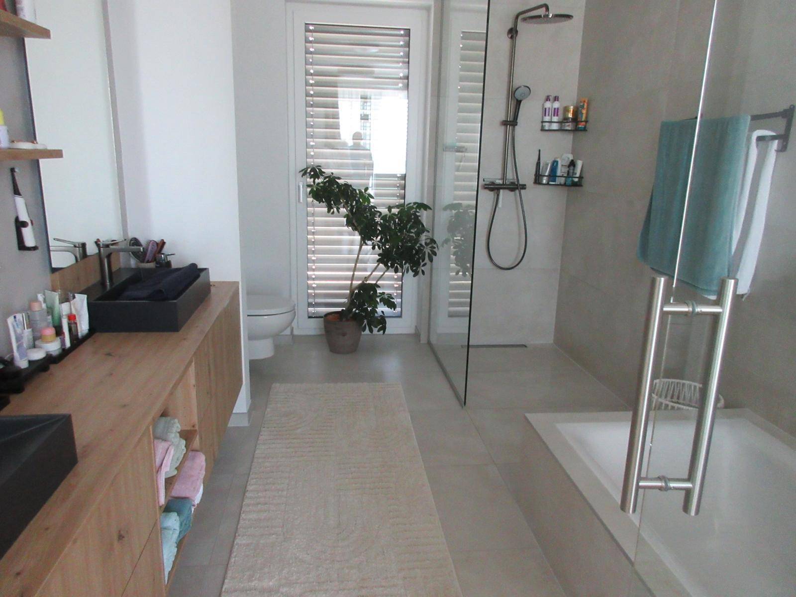 Geräumiges modernes Badezimmer mit Doppelwaschbecken, Dusche und Badewanne.