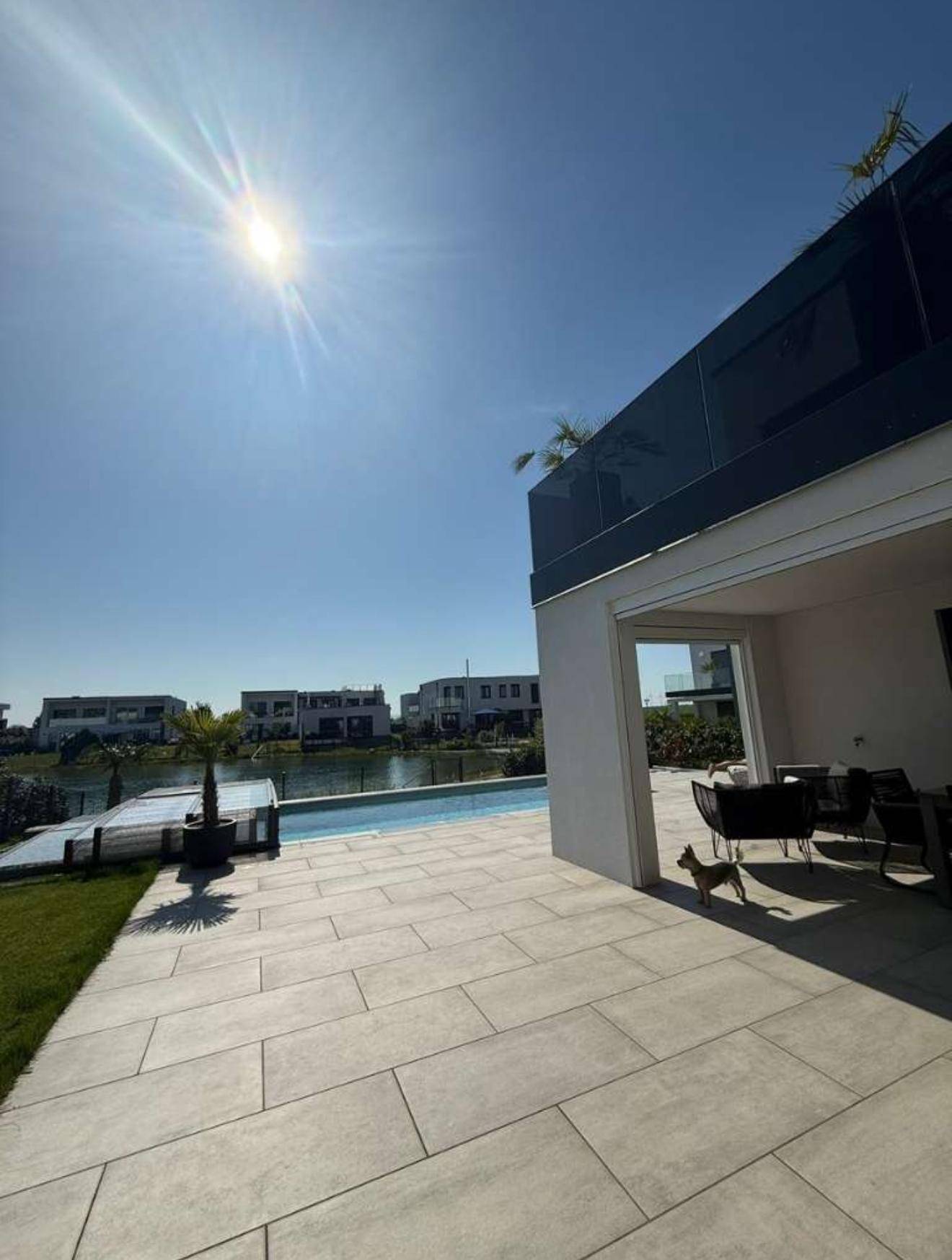 Sonniger Terrassenbereich mit Seeblick und modernem Poolbereich.