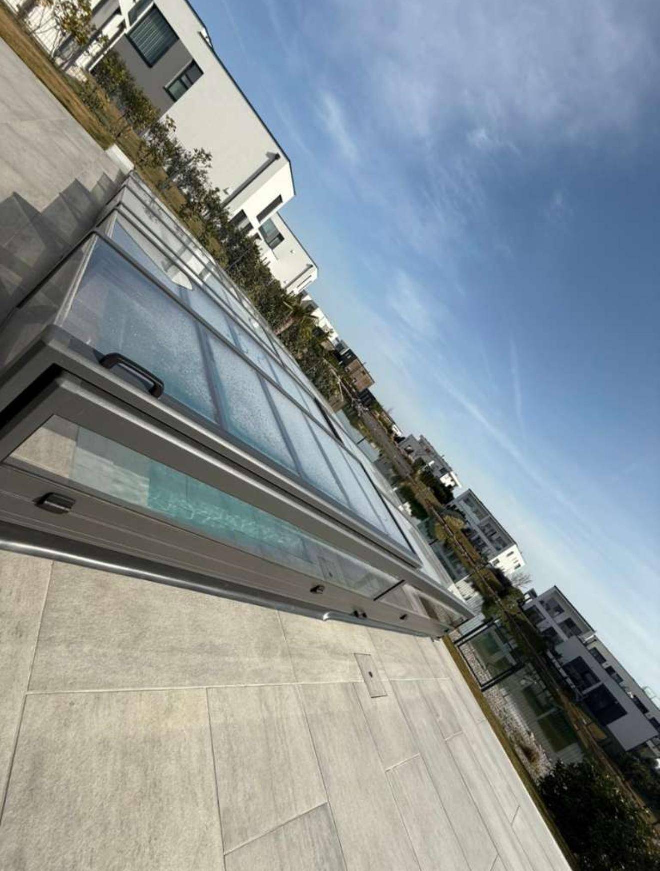 Überdachter Swimmingpool mit moderner Abdeckung und Blick auf die Umgebung.