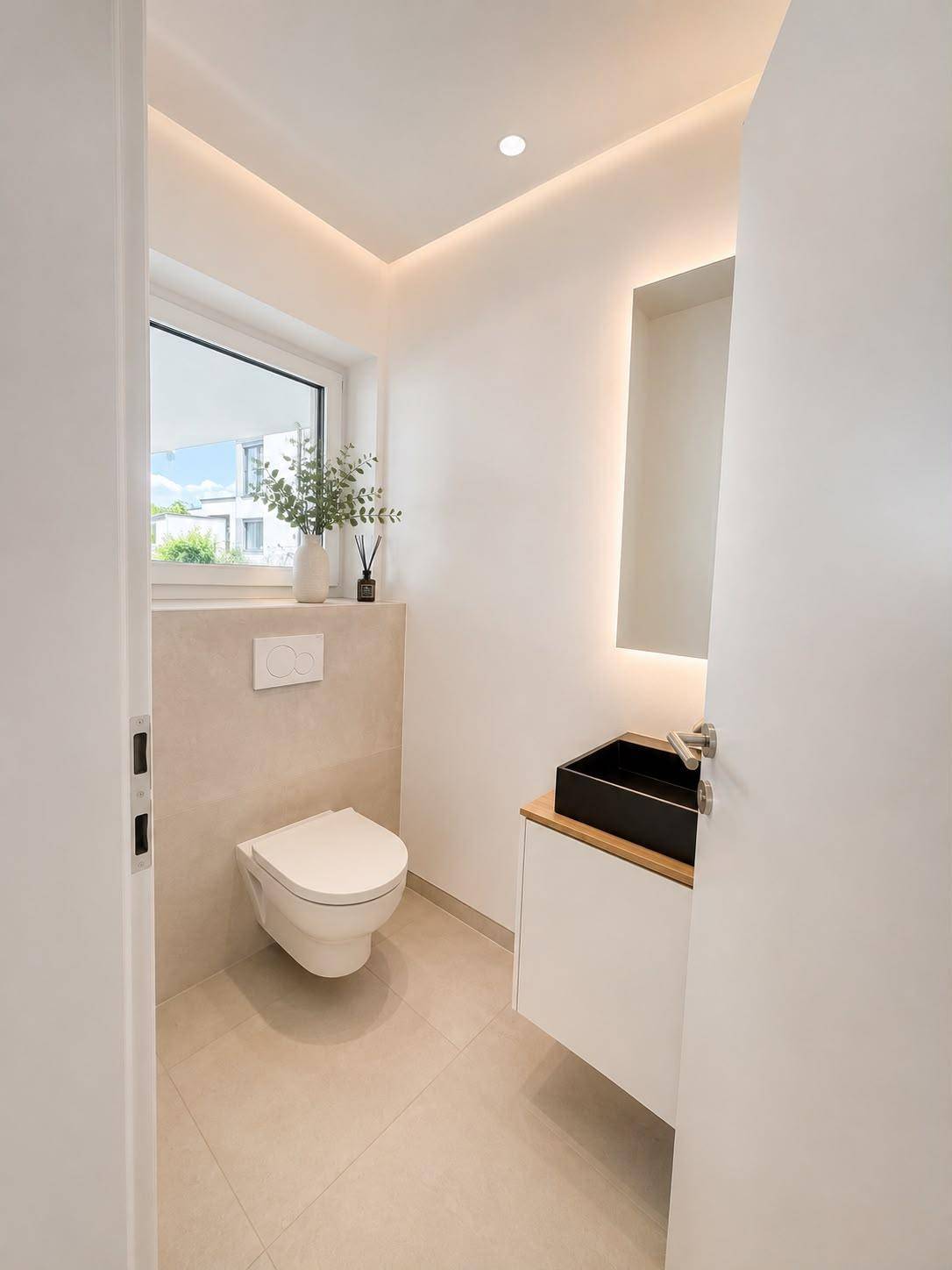 Modernes Gäste-WC mit Wand-WC, kleinem Waschbecken und Fenster.