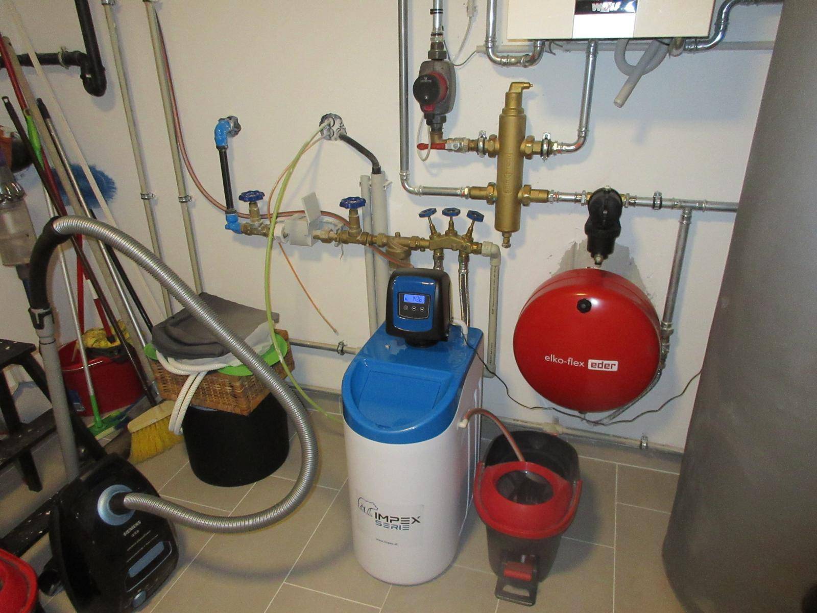 Funktionaler Hauswirtschaftsraum mit Wasserenthärtungsanlage, Rohren und Reinigungsgeräten.
