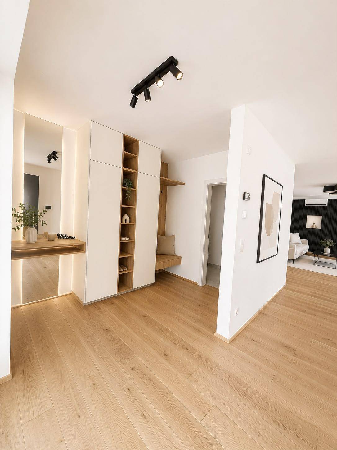 Heller Eingangsbereich mit Holzboden, Einbauschränken und Spiegel.