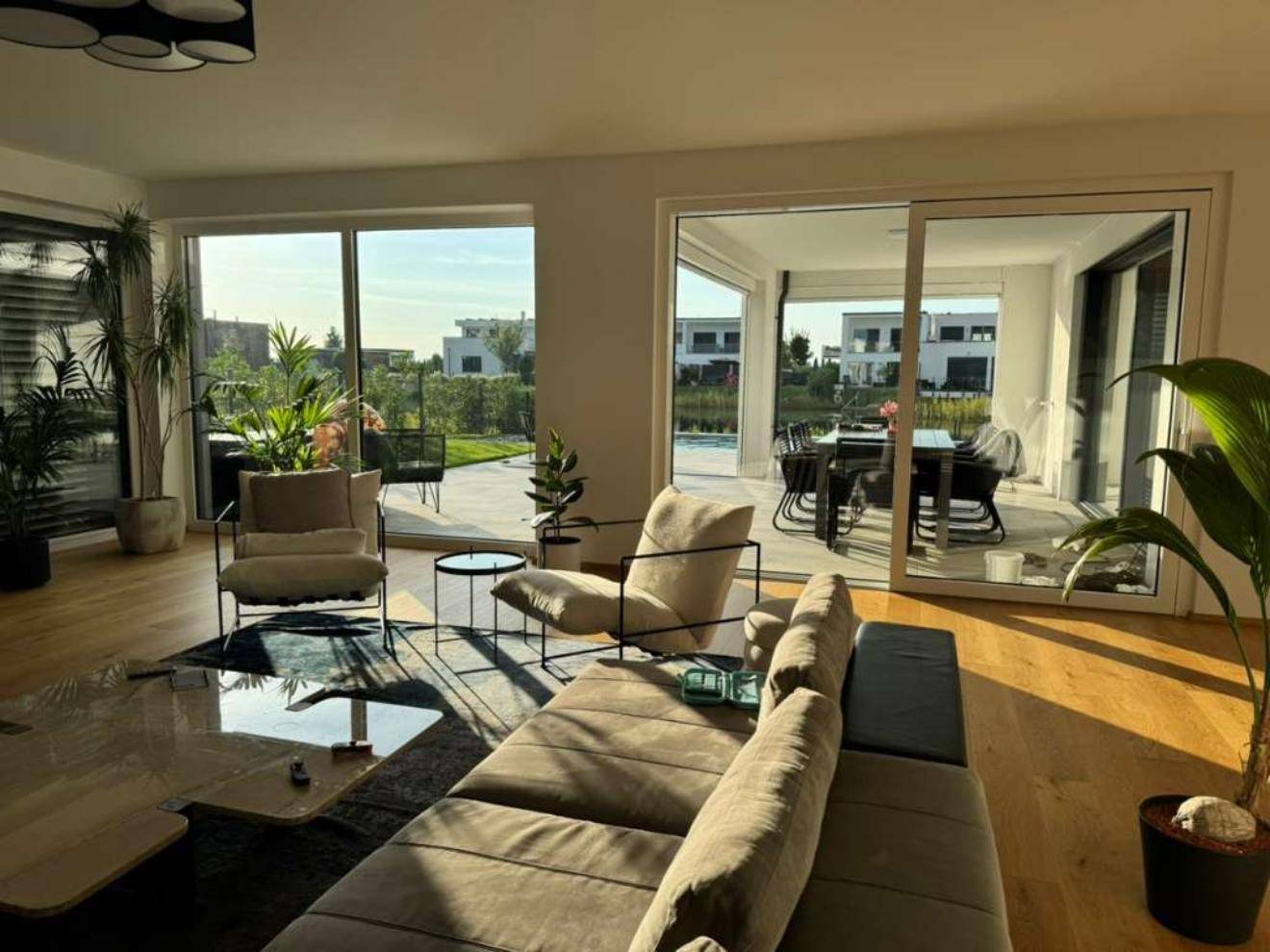 Helles Wohnzimmer mit Holzboden und Zugang zur Terrasse mit Seeblick.