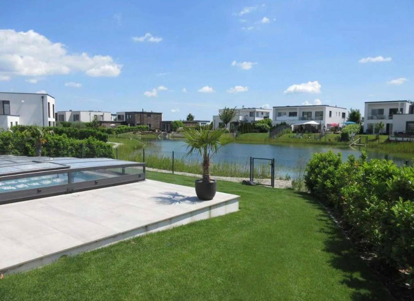 Gepflegter Gartenbereich mit Rasen, Poolabdeckung und Seeblick.