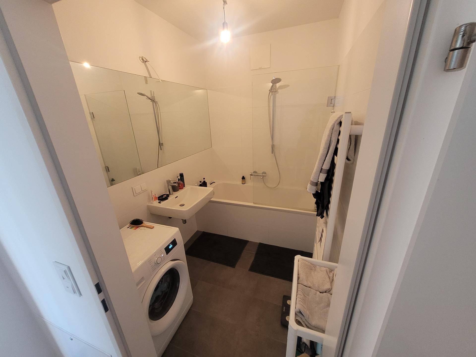 Modernes Badezimmer mit Badewanne, Dusche, Waschbecken und Waschmaschine.