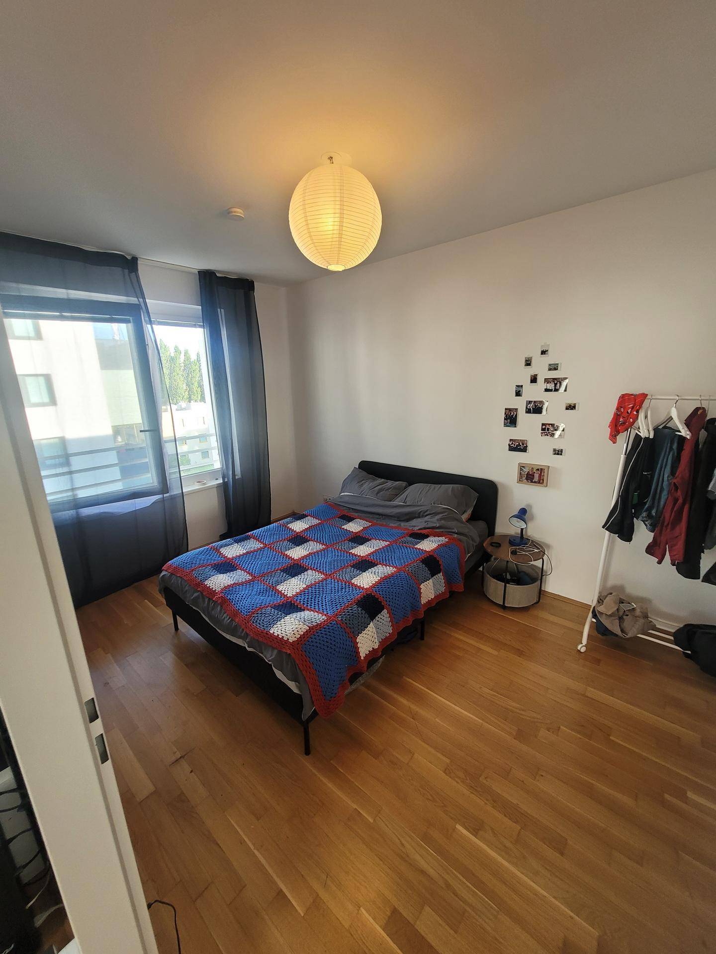 Helles Schlafzimmer mit Fenster, Holzboden und einem bequemen Doppelbett.