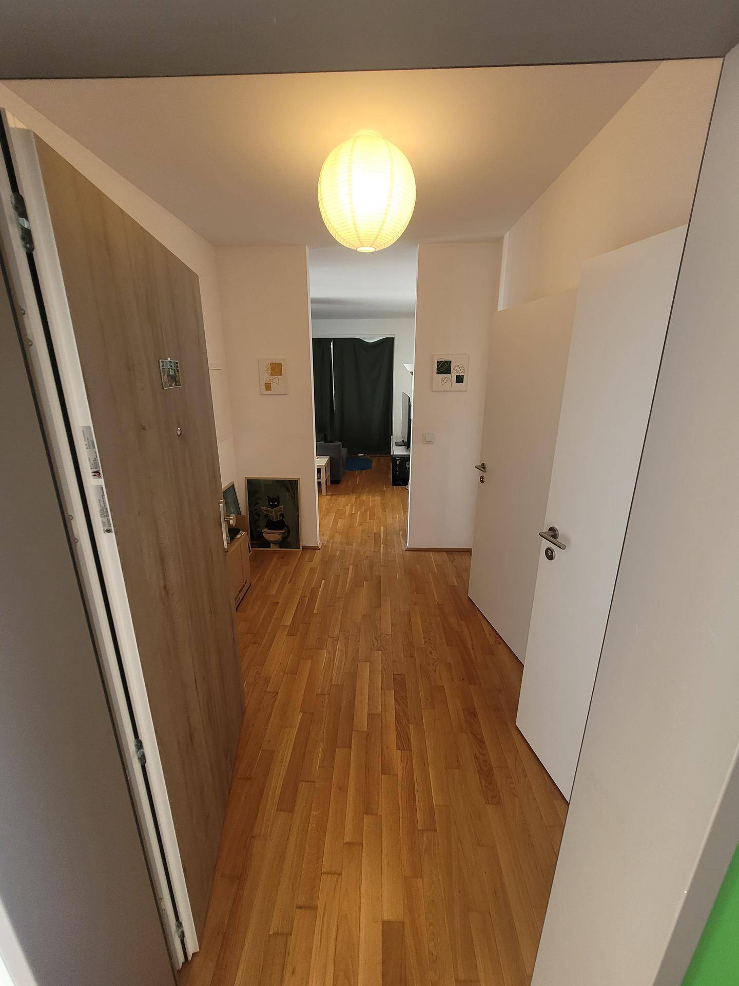 Heller Flur mit Holzboden, der zu den verschiedenen Räumen der Wohnung führt.