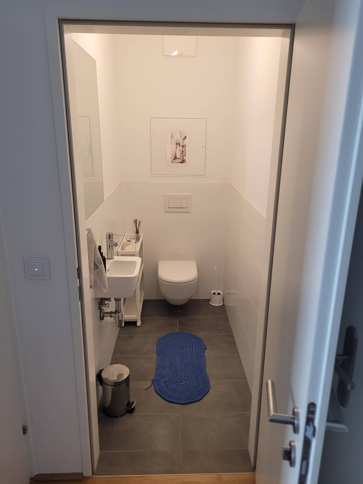 Separates Gäste-WC mit wandhängender Toilette und kleinem Waschbecken.