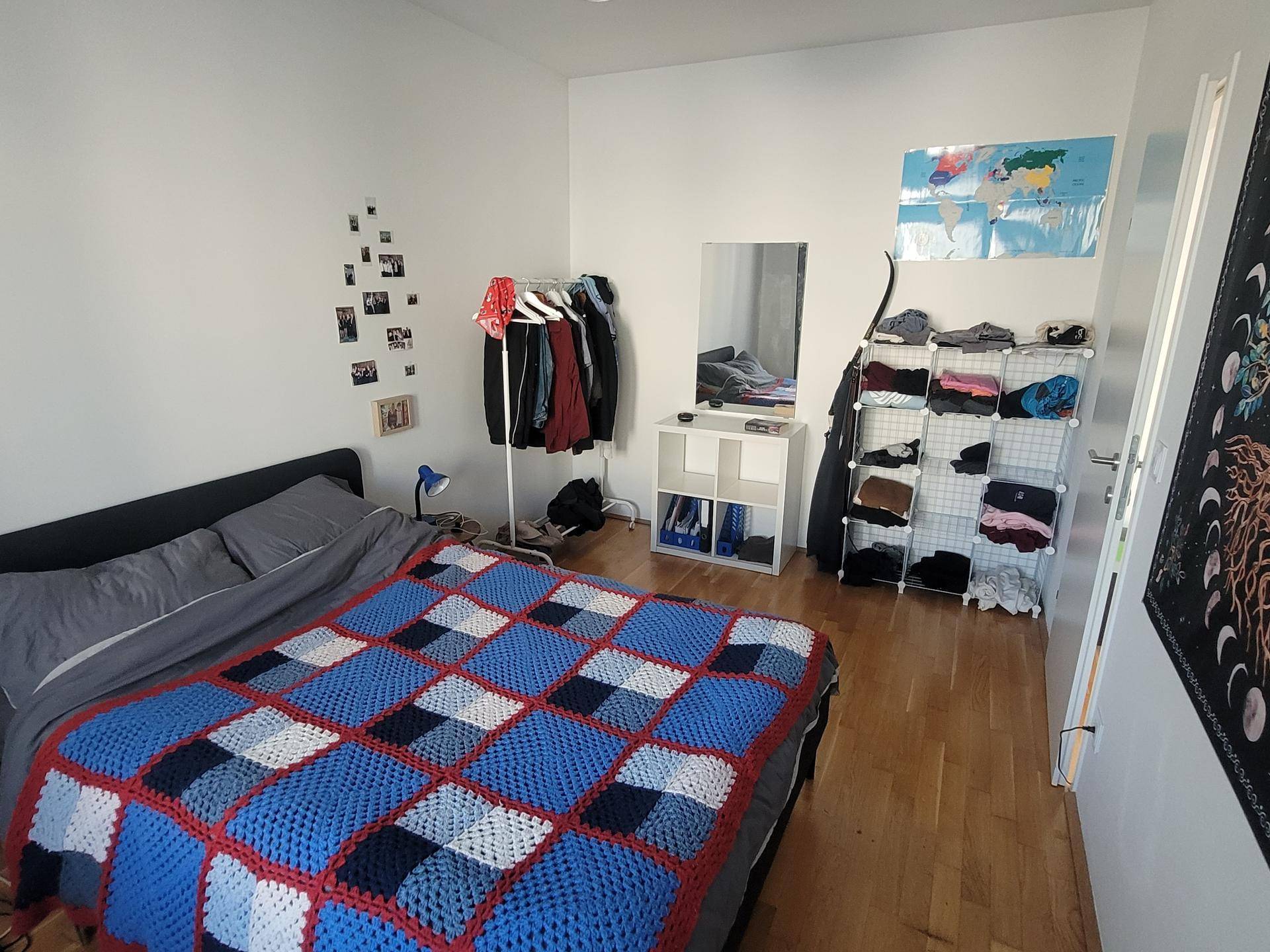 Schlafzimmer mit Holzboden, einem gemütlichen Bett und Stauraum für Kleidung.