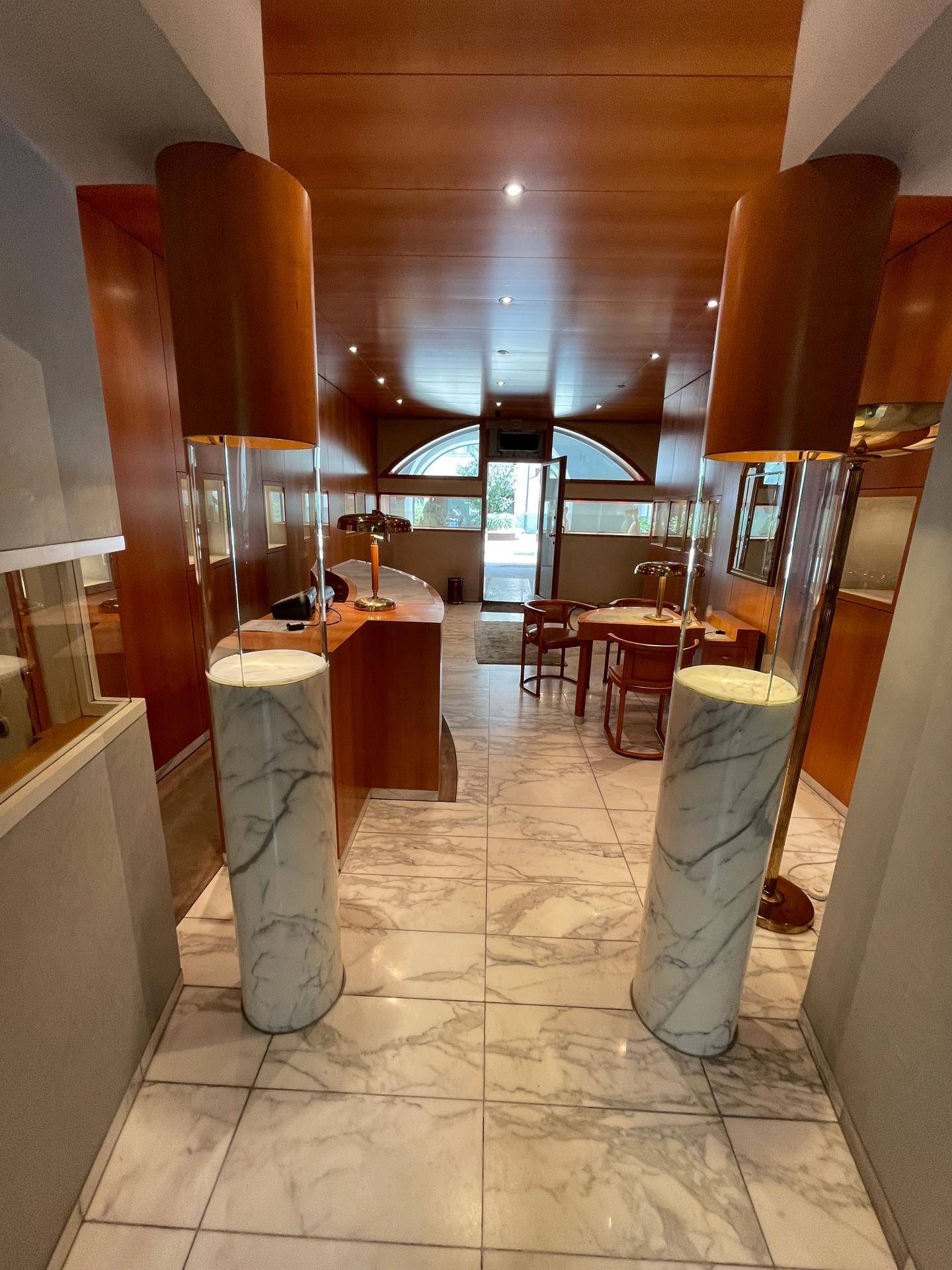 Eingangsbereich des Verkaufsraums mit zwei großen Marmorsäulen und Blick auf den Hauptbereich.