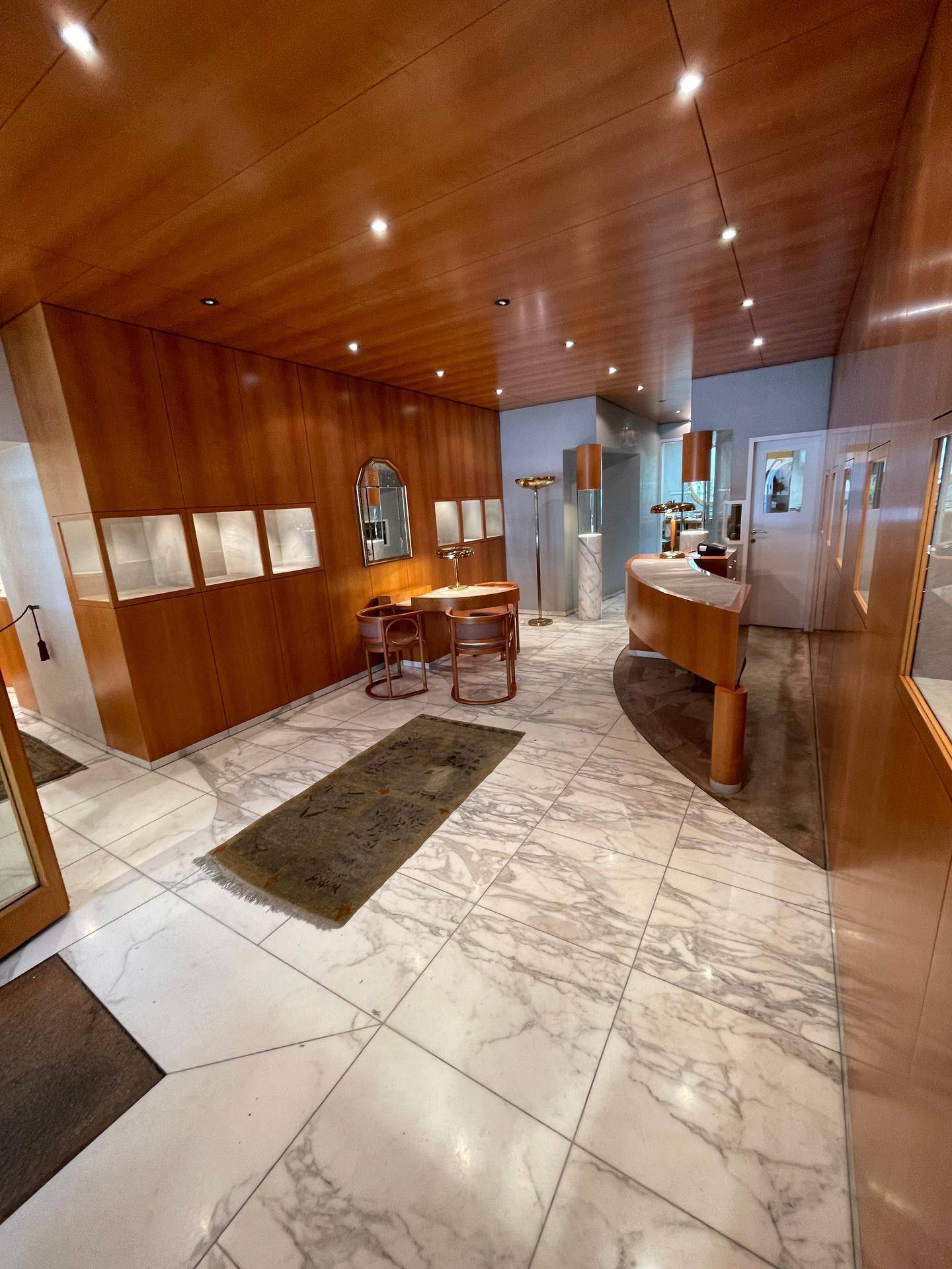 Eleganter Verkaufsraum mit Holzvertäfelung, Marmorboden und stilvollen Möbeln für Präsentationen.