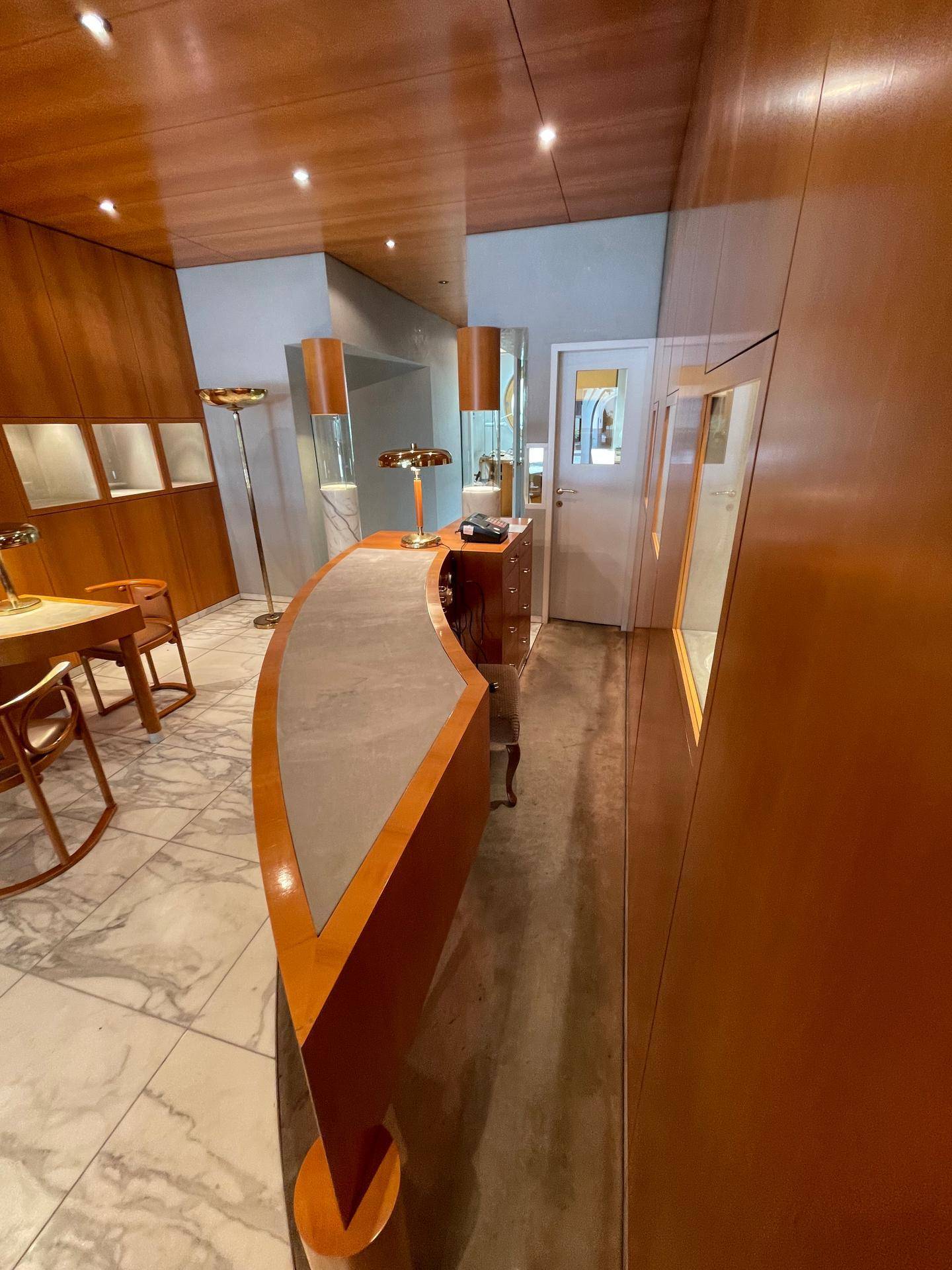Blick auf den geschwungenen Verkaufstresen und eine Tür im eleganten Verkaufsraum mit Holzvertäfelung.