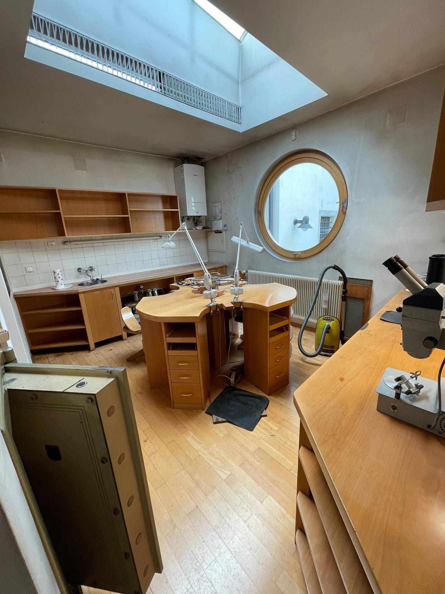 Geräumiger Werkstattbereich mit großem Arbeitstisch, Spülbecken, Regalen und einem Oberlicht für viel Tageslicht.