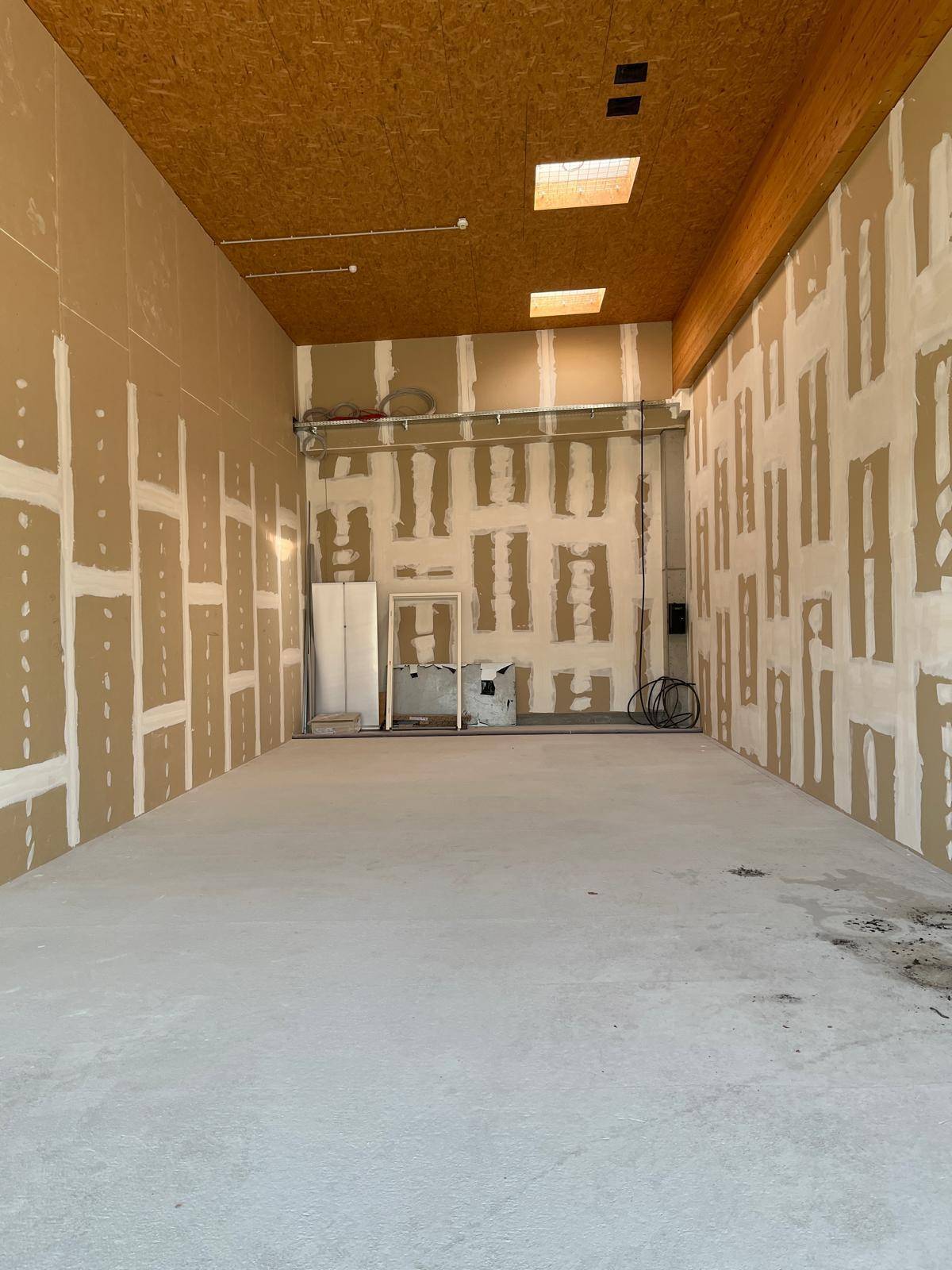 Unfertiger Innenraum eines Gewerberaums mit unverputzten Wänden und OSB-Platten an der Decke.