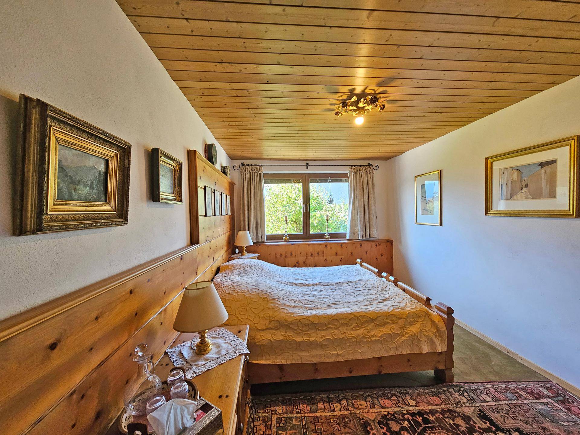 Schlafzimmer mit rustikalem Holzdoppelbett, Holztäfelung an der Wand und einer Holzdecke.