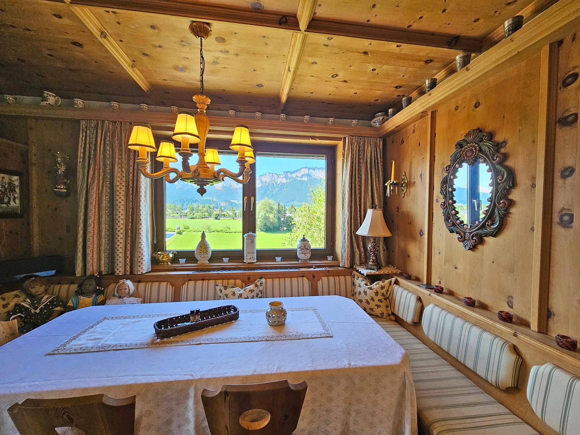 Gemütlicher Essbereich im alpinen Stil mit Holztäfelung, großer Eckbank und Bergblick durch das Fenster.