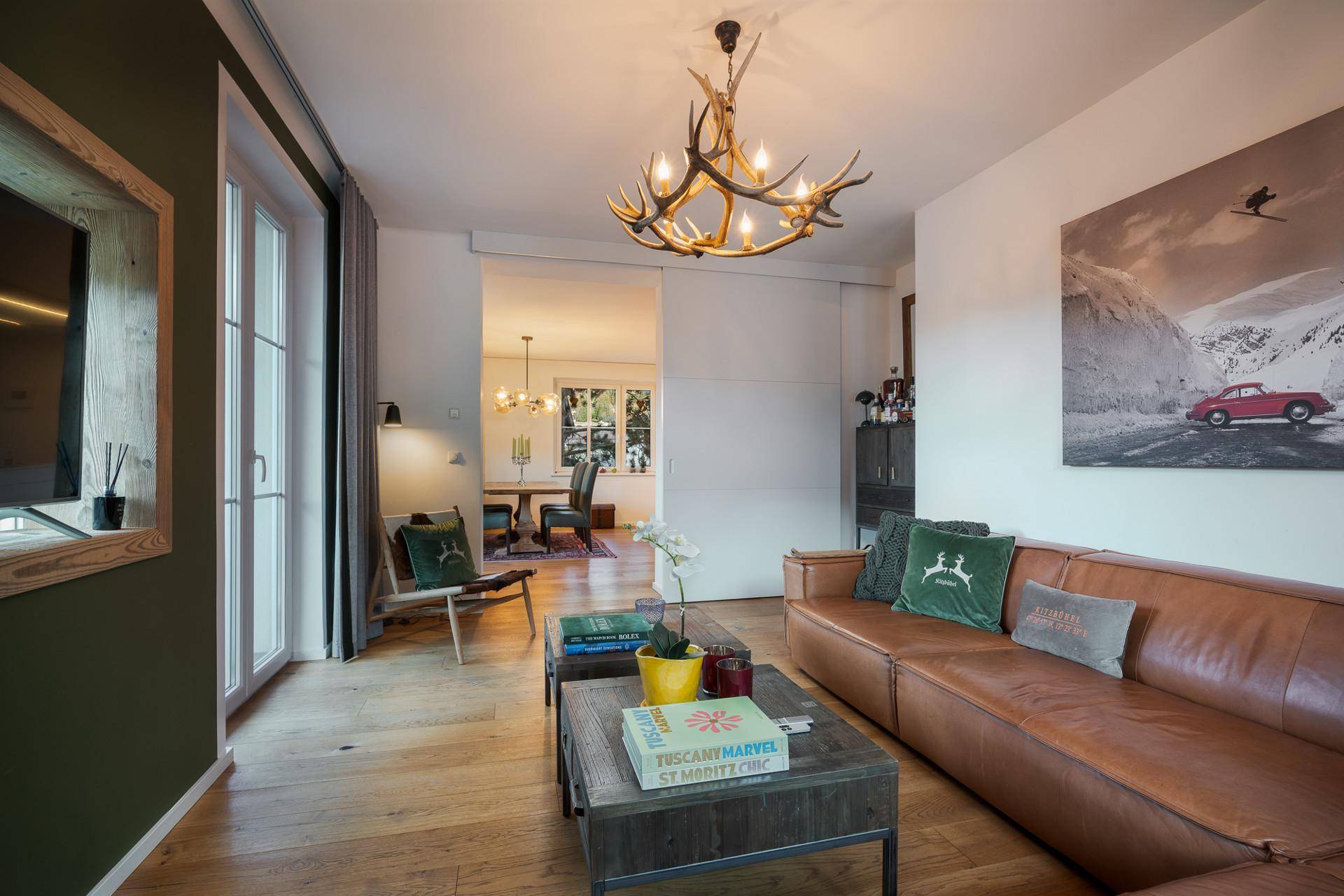 Helles Wohnzimmer mit Ledersofa, Holzboden und Blick auf den angrenzenden Essbereich.